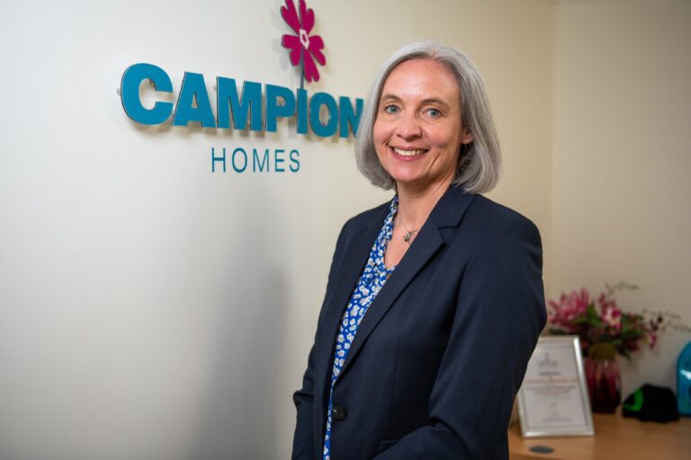 Campion Homes Joint MD Susan Jackson standing in front of company logo